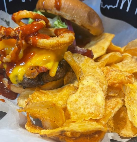 A true taste of the South! Our 1/2lb Angus Steak Burger is smothered in zesty BBQ sauce, blanketed with melted cheddar, and finished with a crispy onion ring. Served on a buttery brioche roll with fresh lettuce, tomato, and onion for a hearty, unforgettable meal.